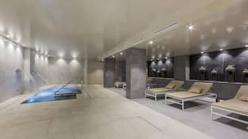 A modern spa area with a pool, lounge chairs, and a wall-mounted sauna.