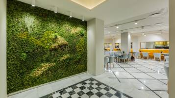 A modern interior with a green wall, checkered floor, and a dining area with chairs and tables.