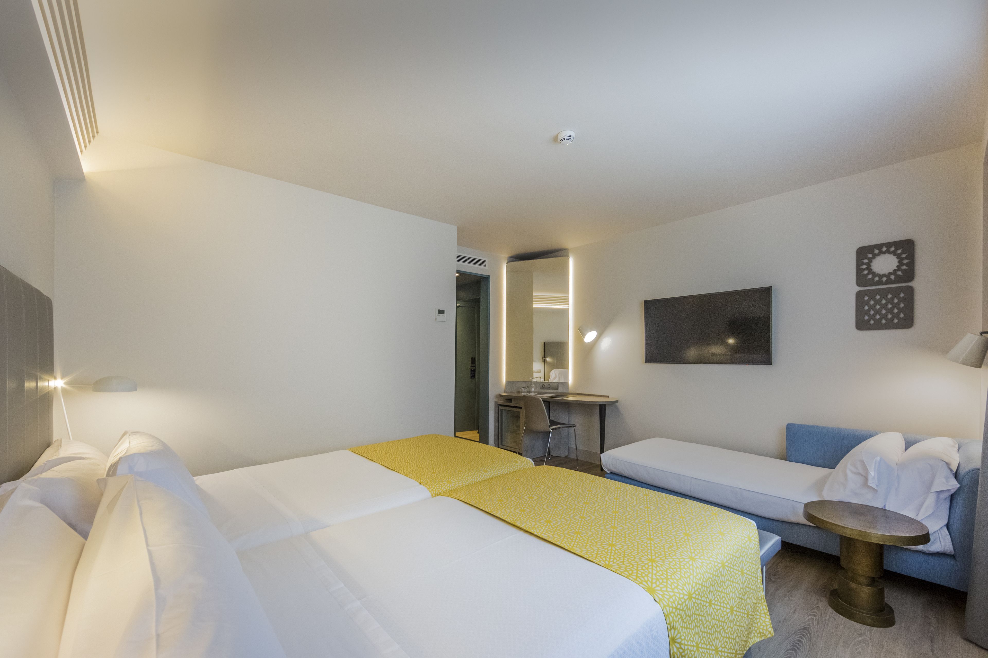 Habitación de hotel con dos camas, un escritorio, una silla, un sofá y una mesita.