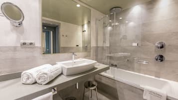 A modern bathroom with a large mirror, a sink, a shower, and a bathtub.