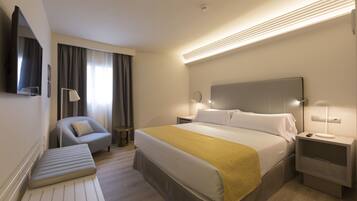 A hotel room with a bed, bedside tables, a chair, a bench, and a TV.