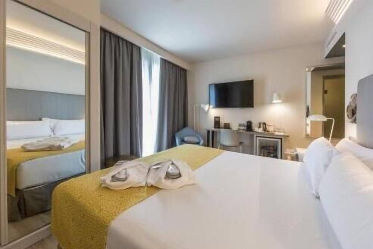 Une chambre d’hôtel équipée d’un lit, d’un bureau, d’une chaise, d’une télévision et d’un miroir.