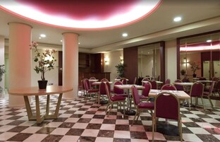 Eine Hotelhalle mit Schachbrettmuster-Boden, runden Tischen und violetten Stühlen.