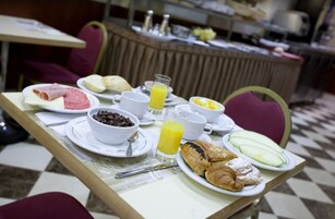 Una tavola imbandita per la colazione, con piatti di cibo tra cui croissant, frutta e una ciotola di gocce di cioccolato.