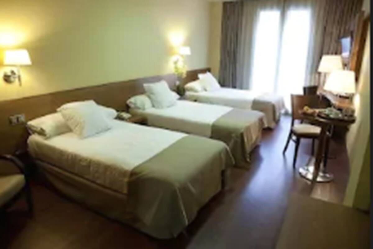 Una habitación de hotel con dos camas individuales, un escritorio y una silla.