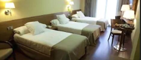A hotel room with two single beds, a desk, and a chair.
