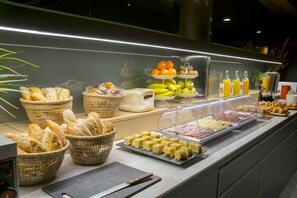 Un bufé con diversos alimentos, incluyendo pan, frutas y pasteles.