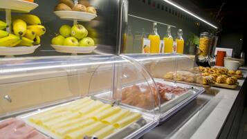 Un bufé con diversas opciones de comida, como frutas, bollería y bebidas.