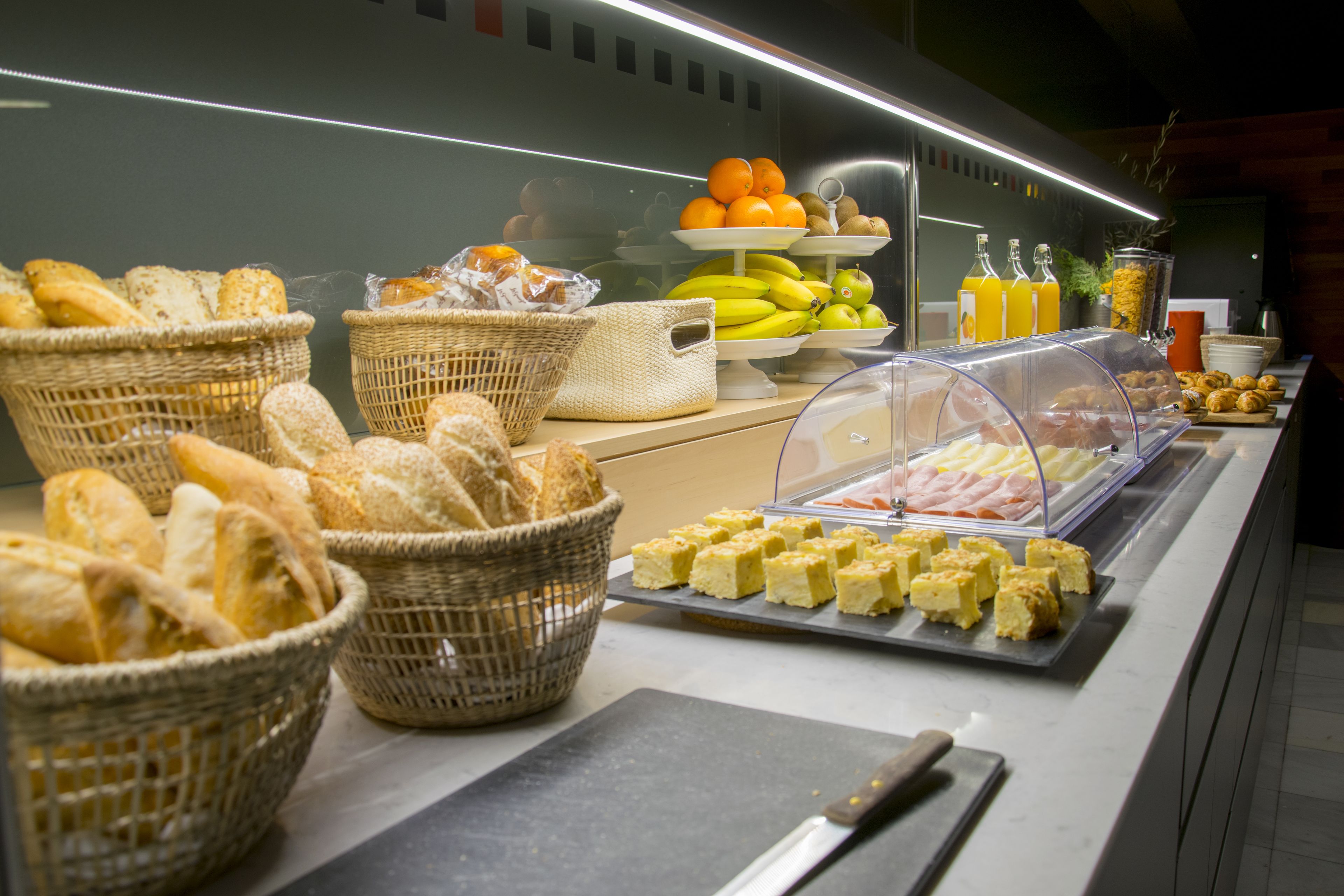 Un bufé con diferentes opciones de comida, incluyendo pan, queso, frutas y bebidas.