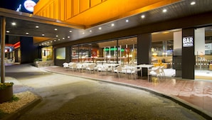 An outdoor seating area with tables and chairs, a Burger King sign, and a Bar America sign. - Hotel America (Igualada)