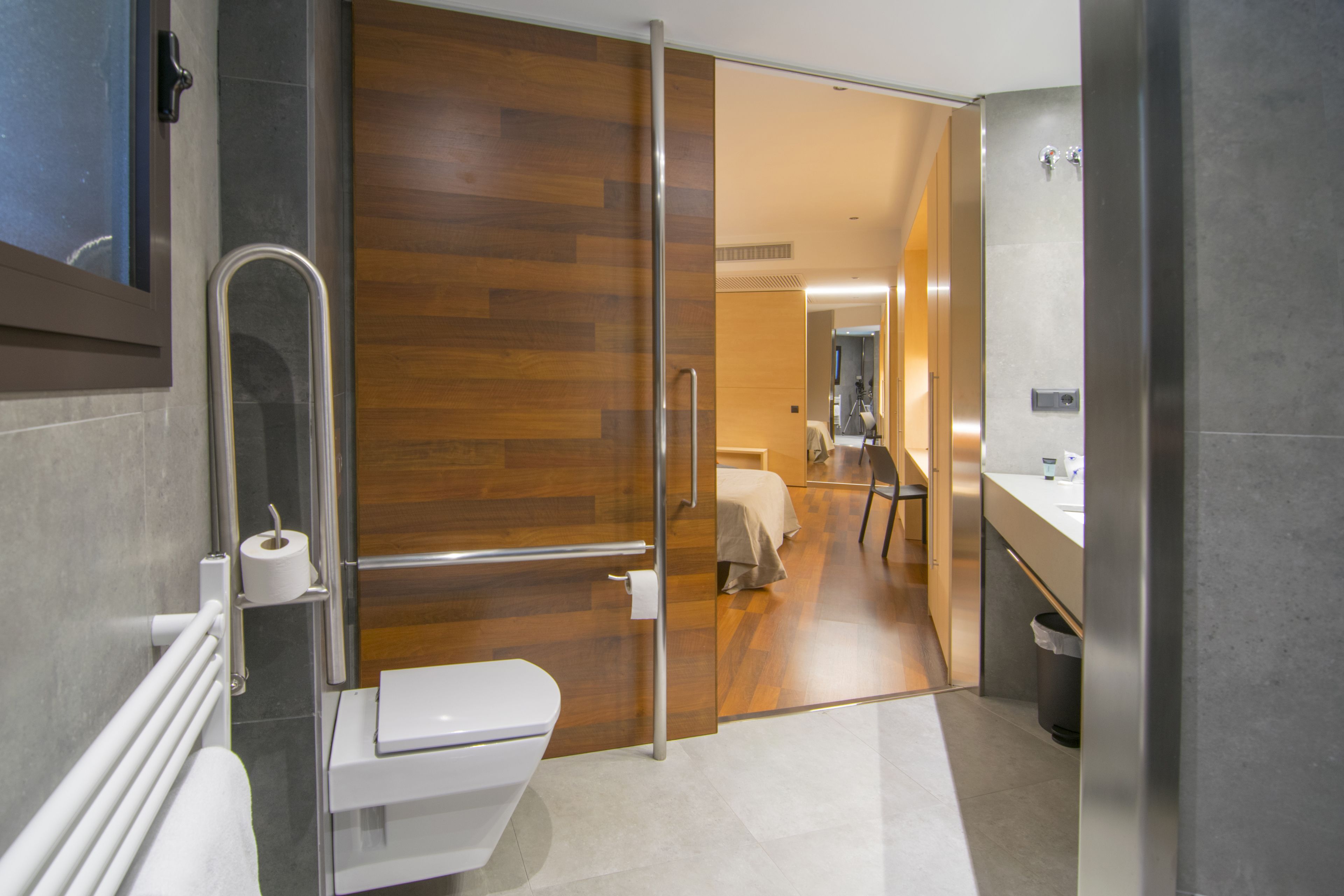 Un baño moderno con mampara de vidrio, inodoro, lavamanos y zona de ducha.