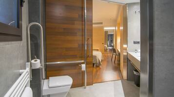 Un baño moderno con mampara de vidrio, inodoro, lavamanos y zona de ducha.