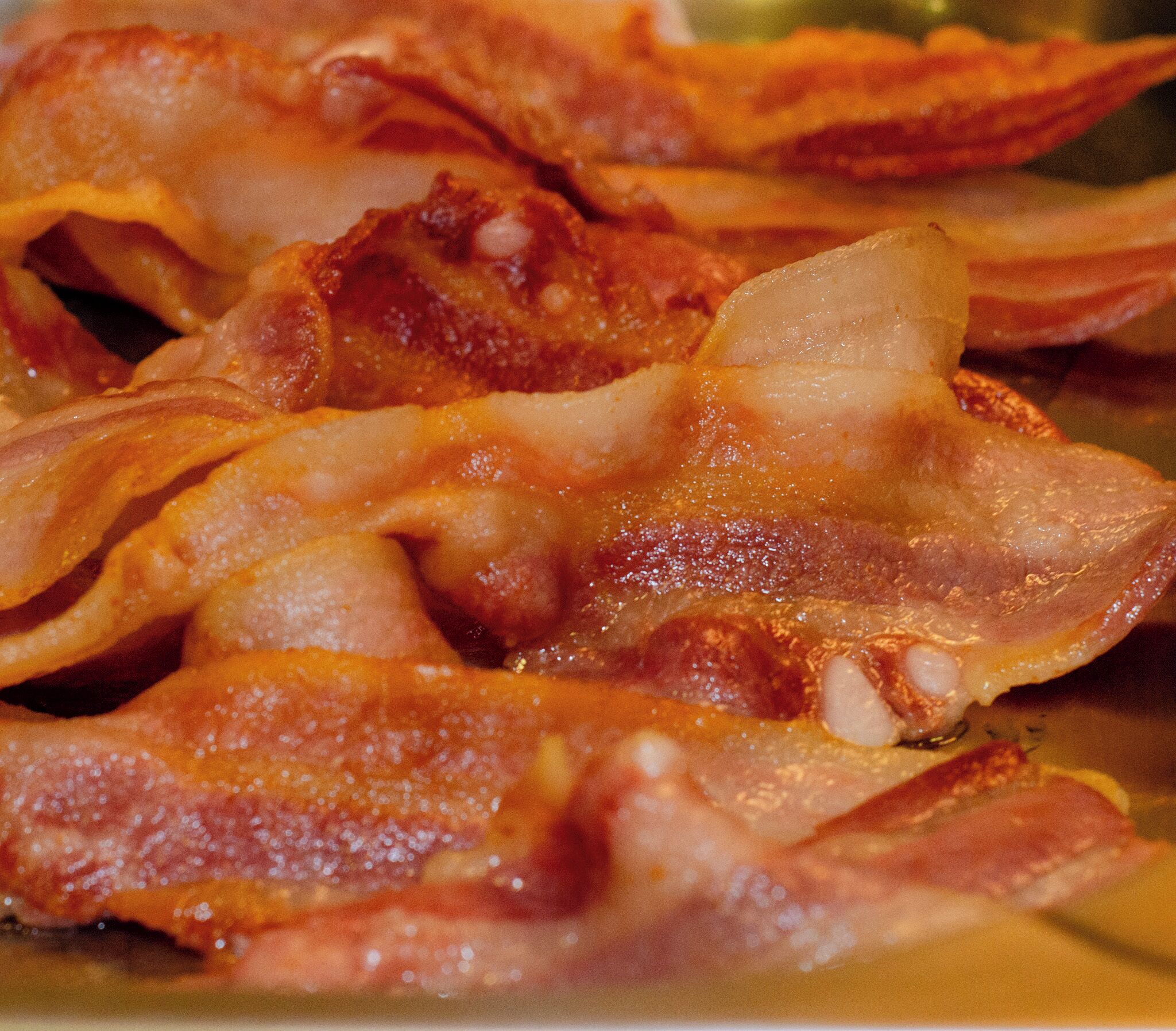 Une vue rapprochée de bacon cuit, où l’on peut voir la graisse et les épices.