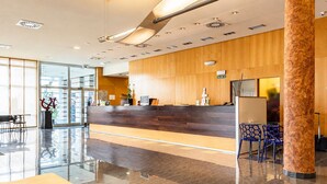 A modern reception area with a wooden counter, a glass door entrance, and a seating area with a bench. - Hotel Andia (Orcoyen)