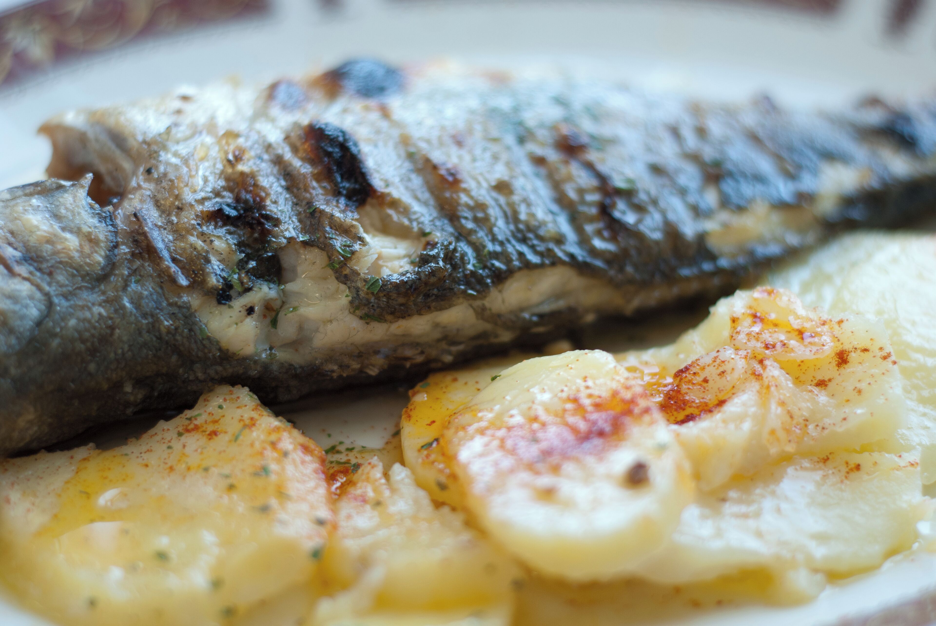 Ein gegrillter Fisch mit Bratkartoffeln.