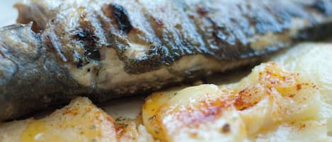 Un poisson grillé, accompagné de pommes de terre rôties.