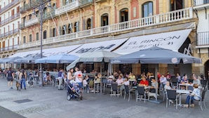 An outdoor café with outdoor seating and umbrellas, located in front of a building with ornate architecture. - Hotel Andia (Orcoyen)