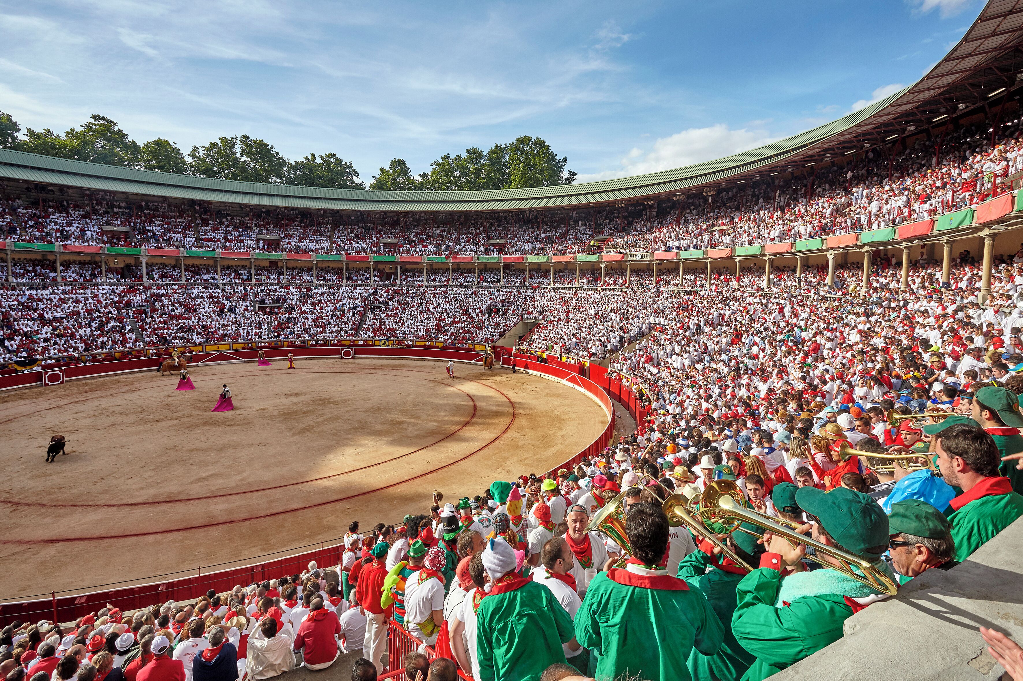 A large bullfighting arena with a crowd of spectators and performers in traditional attire.