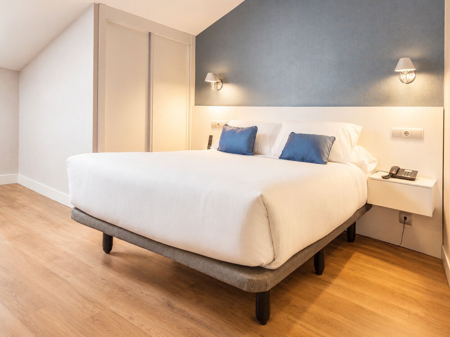 Ein modernes Schlafzimmer mit Bett, Nachttischlampen, Telefon und Kleiderschrank.