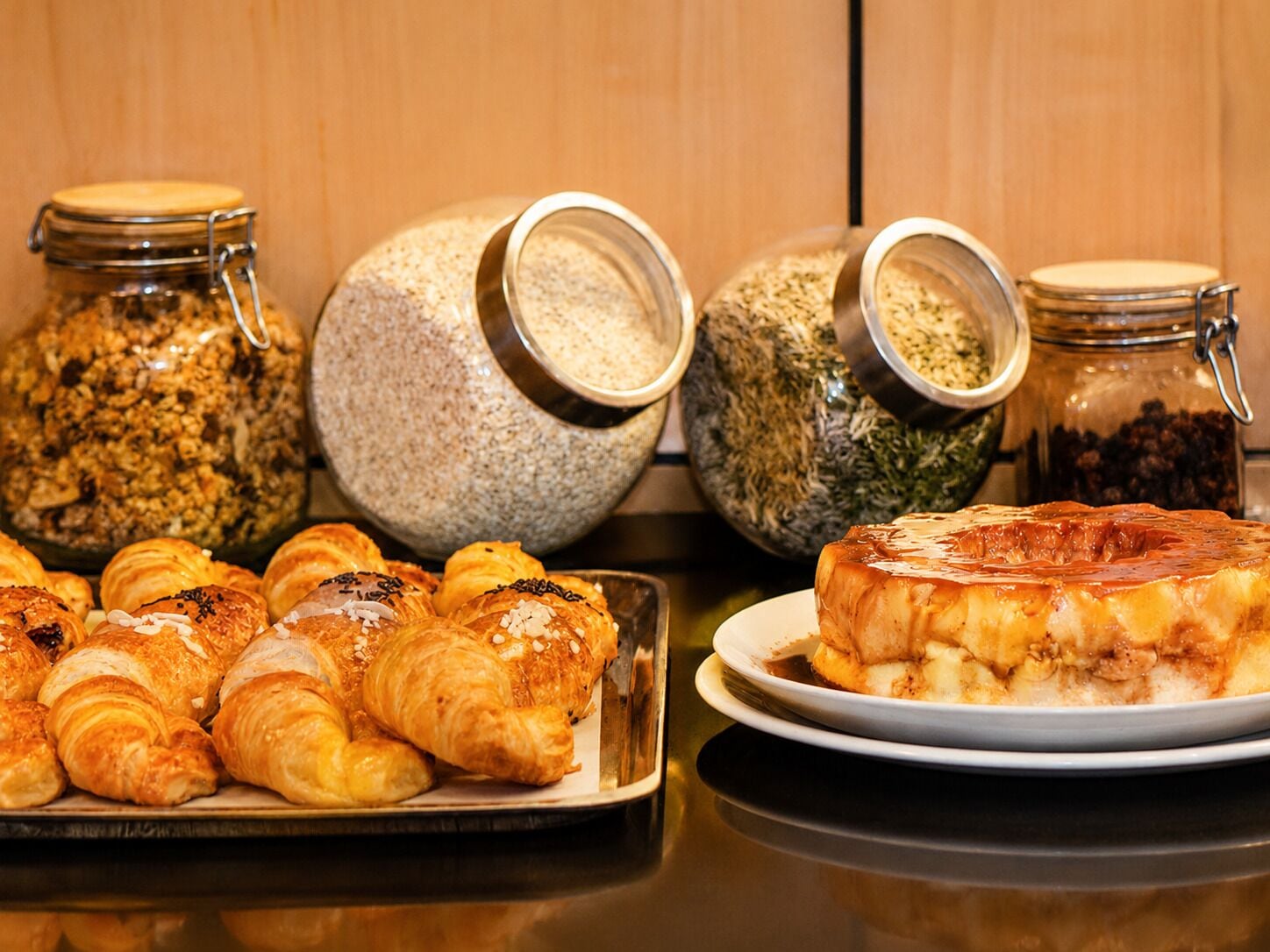 A breakfast buffet with pastries, a cake, and various food items in jars.