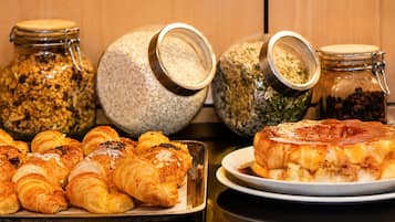 A breakfast buffet with pastries, a cake, and various food items in jars.