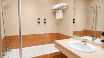 A modern bathroom with a glass-enclosed shower, a bathtub, a sink, and a mirror.