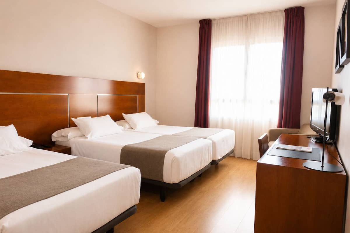 A hotel room with two beds, a desk with a computer, and a television.
