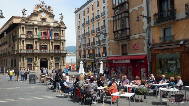 A bustling outdoor cafe with tables and chairs, surrounded by historic buildings with balconies and ornate facades. - Hotel Andia (Orcoyen)