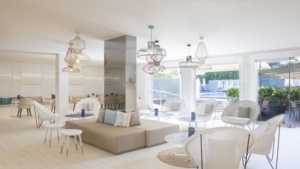 A spacious living area with a large sectional sofa, white chairs, and a dining table.