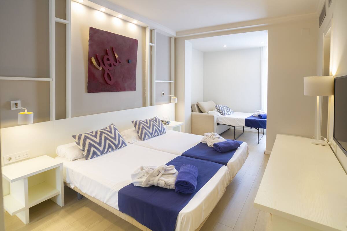 Een hotelkamer met een bed, nachtkastjes, een bureau en een televisie.