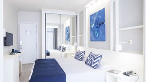 A modern hotel room with a large bed, a desk, and a television.