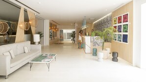 A modern hotel lobby with a reception desk, a white sofa, and a coffee table.