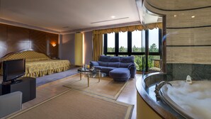 A modern hotel room with a large bed, a sofa, a TV, a coffee table, and a bathtub. - EXE Auriense (Ourense)