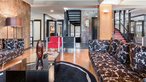 A spacious living area with a modern sofa, a red chair, and a coffee table. There is a staircase leading to an upper level. - EXE Auriense (Ourense)