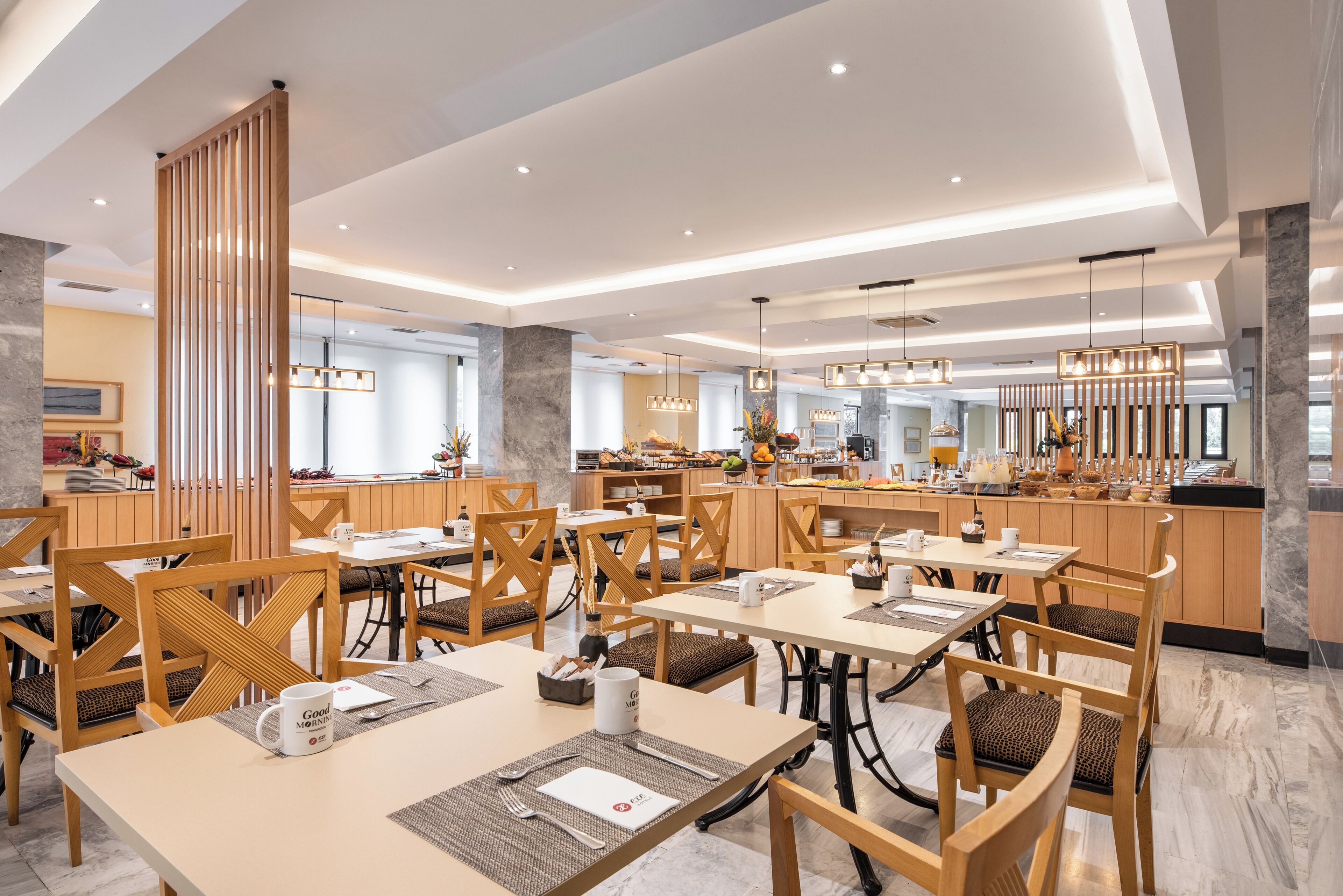 Un'area ristorazione moderna con tavoli e sedie in legno, un bancone centrale e un pannello decorativo in legno.