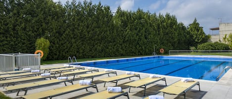Een seizoensgebonden buitenzwembad en ligstoelen