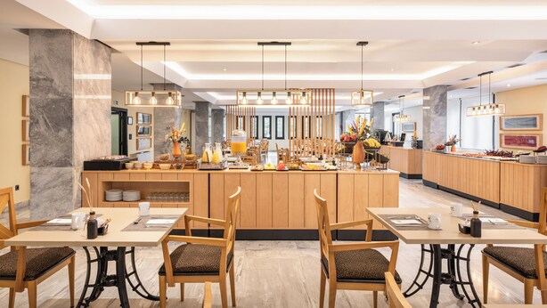 A modern hotel lobby with a central bar area, wooden furniture, and a marble floor. - EXE Auriense (Ourense)