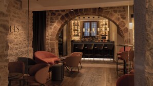 A cozy interior with stone walls, a bar area, and seating arrangements. - Gran Hotel Barcino (Barcelona)