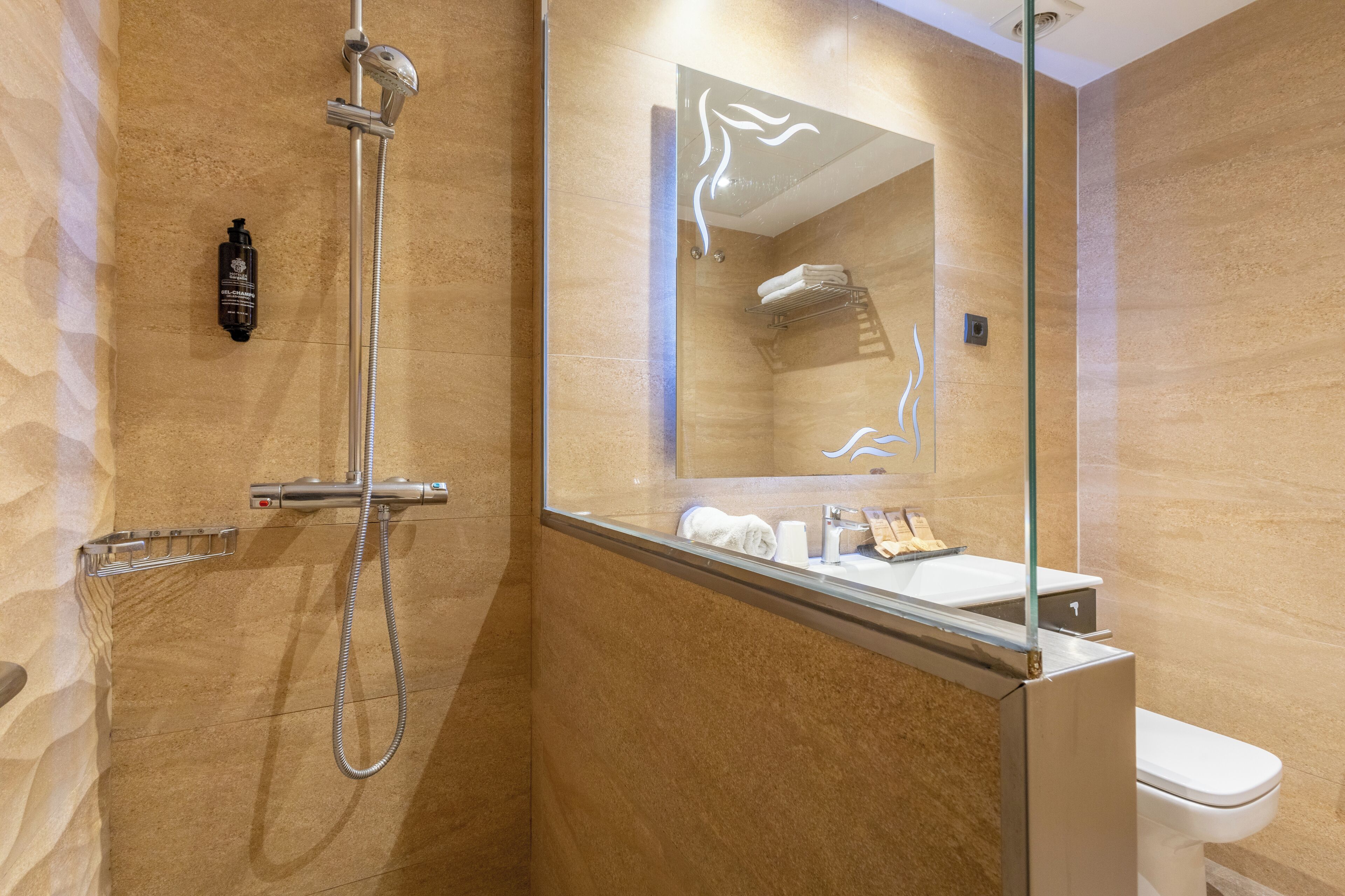 Un baño moderno con ducha de vidrio, tocador con espejo y retrete.