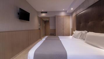 A hotel room with two beds, a flat-screen TV mounted on the wall, and a large wardrobe.