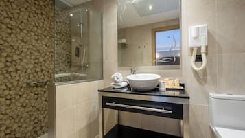 Un baño moderno con ducha de vidrio, lavamanos blanco y retrete.