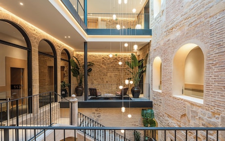 A multi-level atrium with stone walls, a staircase, and hanging lights.