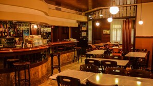 Un espace bar avec un comptoir, des tabourets et des tables. Des panneaux indiquent les plats proposés au menu, et il y a également un espace dédié à la détente et aux échanges.