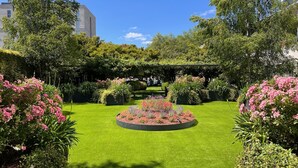 A well-maintained garden with a central circular flower bed, surrounded by lush greenery and trees. - Oca Puerta del Camino Hotel (Santiago de Compostela)