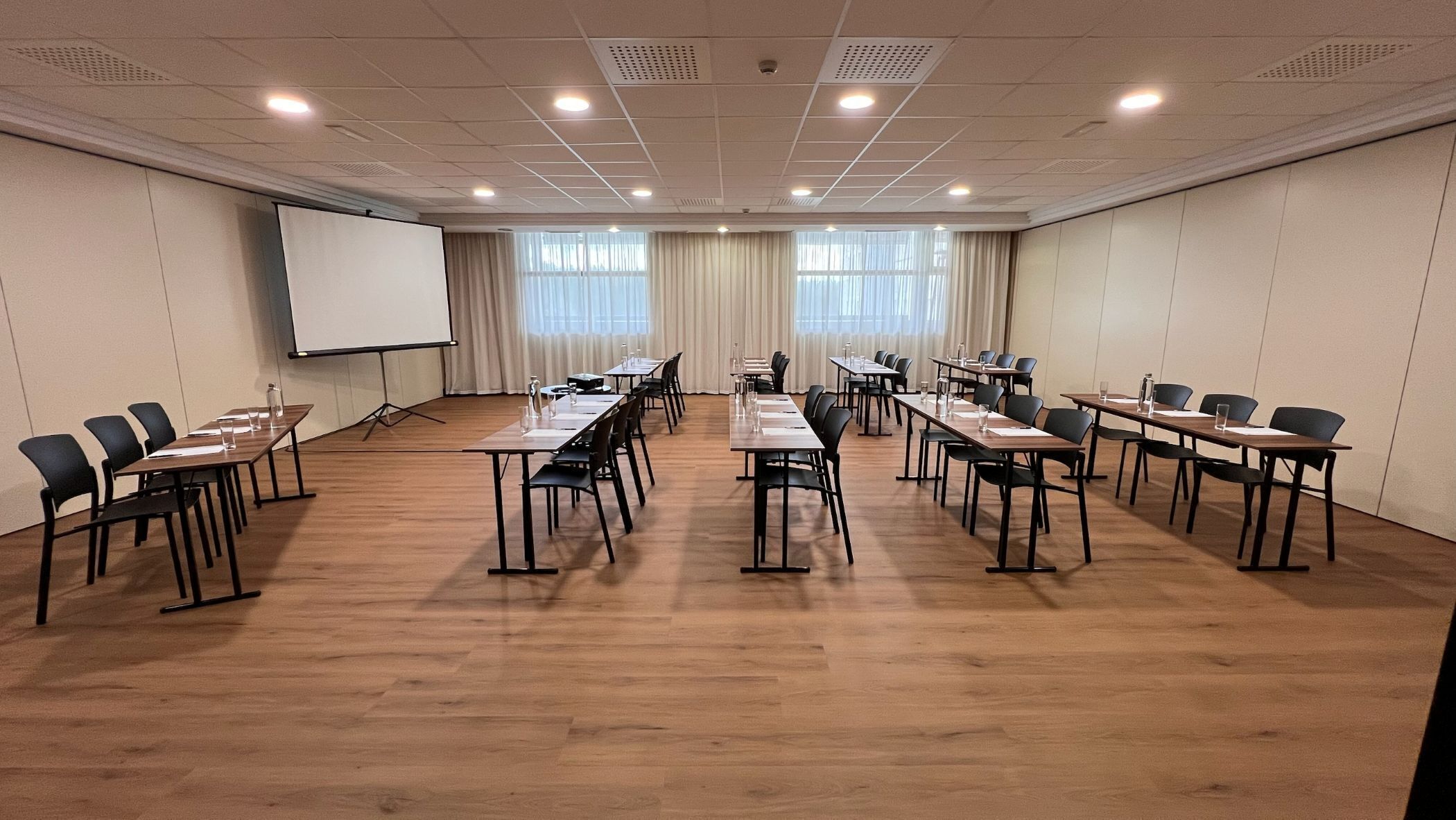 A conference room with multiple tables and chairs, a whiteboard, and a projector screen.