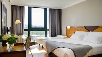 Een hotelkamer met twee bedden, een bureau met lamp, een stoel en uitzicht op het omliggende landschap.