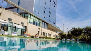A hotel with a swimming pool, outdoor seating, and a modern building facade. - Oca Puerta del Camino Hotel (Santiago de Compostela)