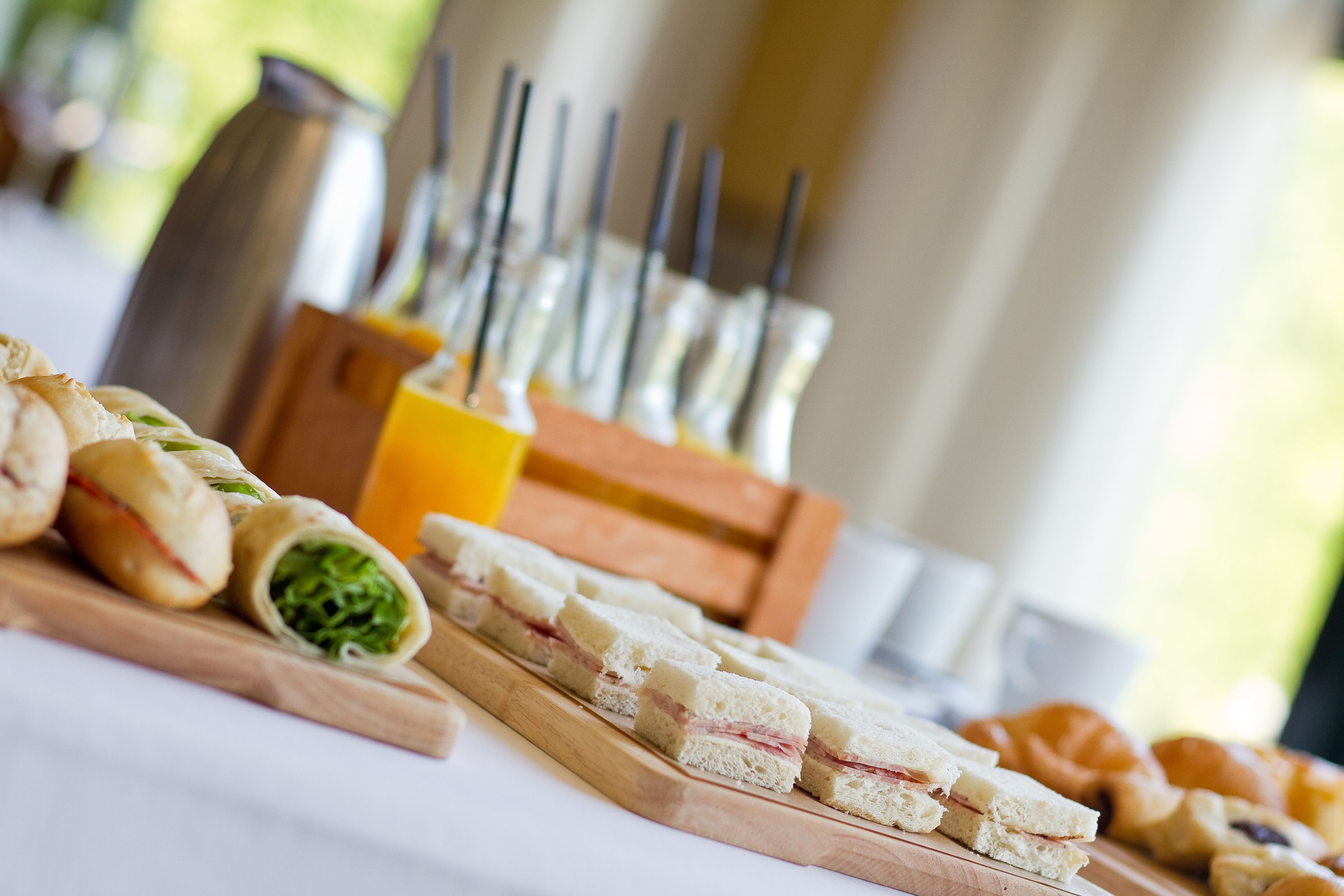 A table with sandwiches, pastries, and a juice dispenser.
