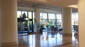A spacious lobby with large windows, a reception desk, and a seating area. - Oca Puerta del Camino Hotel (Santiago de Compostela)