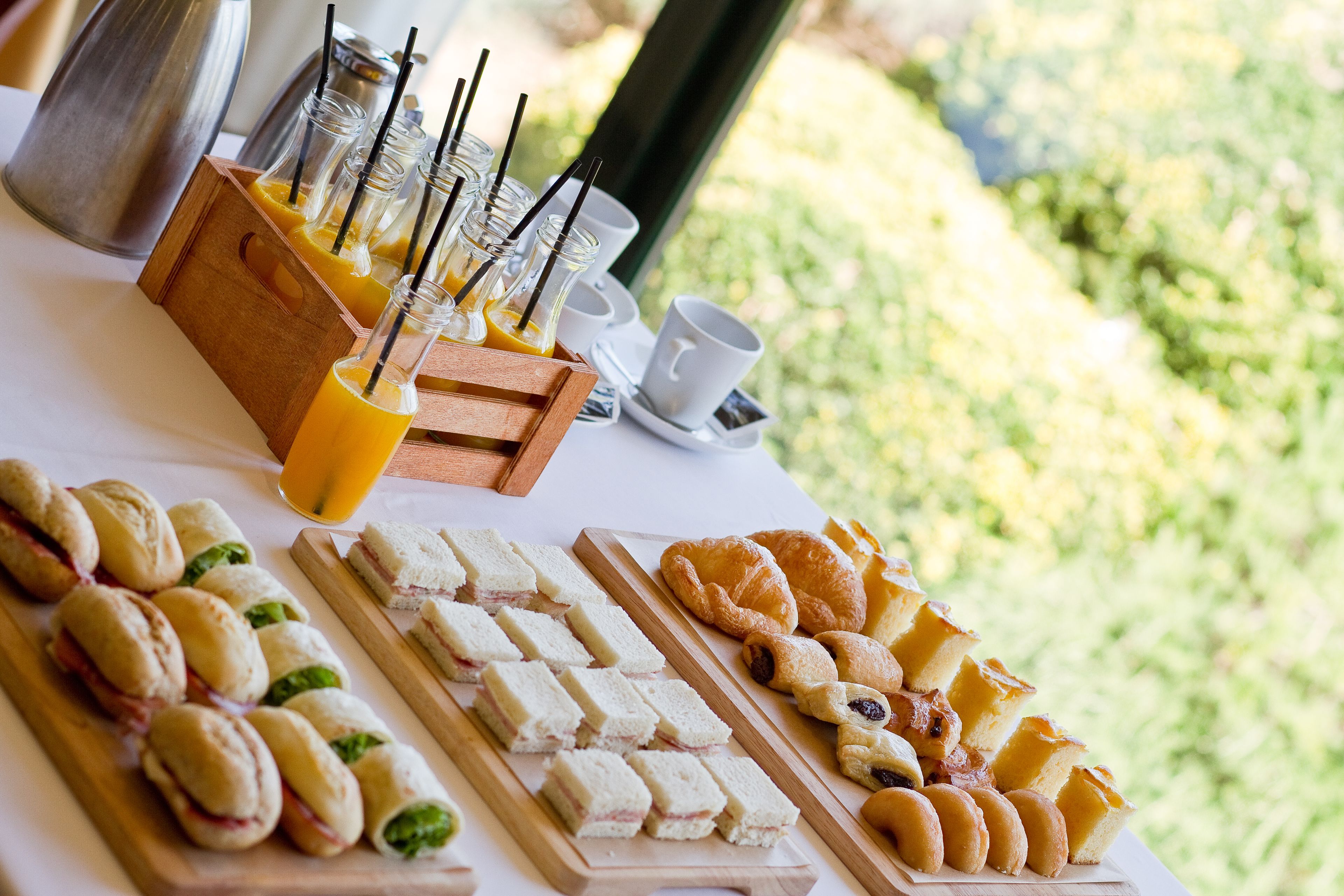 Een ontbijtbuffet met belegde broodjes, gebak en sinaasappelsap.
